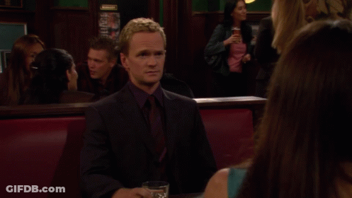 A Man In A Suit Sits At A Table With A Glass Of Whiskey And A Bowl Of Food GIF