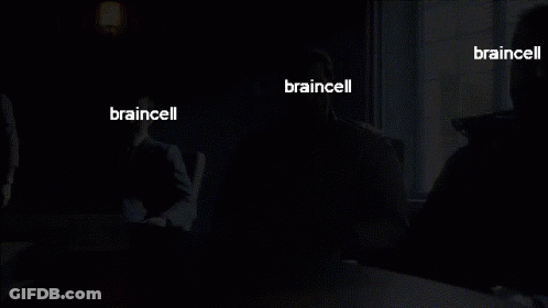 A Man In A Suit Sits At A Table With The Words Braincell On His Face GIF