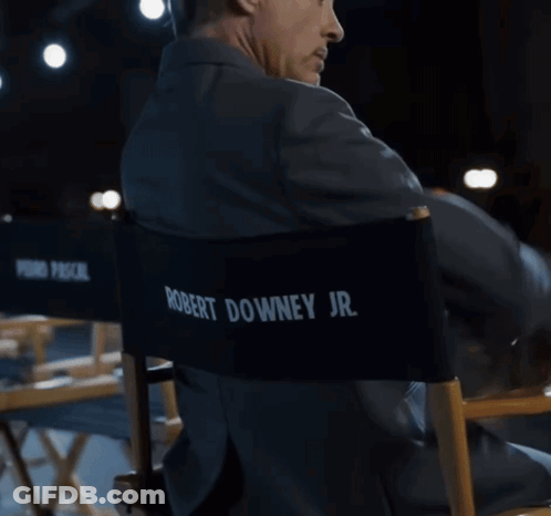 A Man In A Suit Sits In A Director 'S Chair With Pedro Pascal Jr. Written On The Back GIF