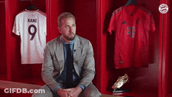 A Man In A Suit Sits In A Locker With Kane Jerseys GIF
