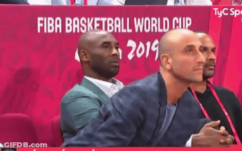 A Man In A Suit Sits In Front Of A Sign That Says Fiba Basketball World Cup 2019 GIF