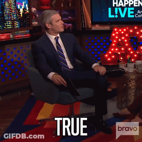 Man In Suit Sitting In Front Of True Sign GIF