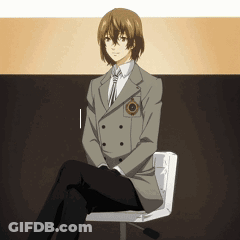 A Man In A Suit Sits On A Chair With His Legs Crossed GIF
