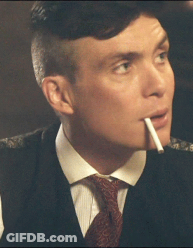 A Man In A Suit Smoking A Cigarette In His Mouth GIF