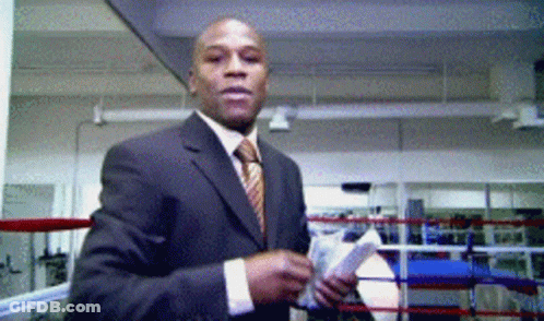 A Man In A Suit Stands In A Boxing Ring GIF