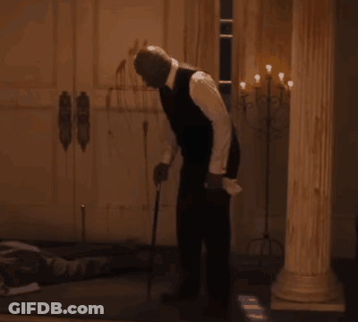 A Man In A Suit Stands In A Dark Room GIF
