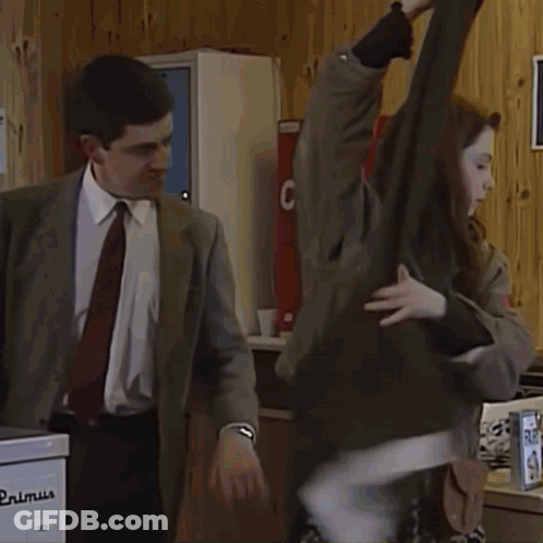 A Man In A Suit Stands In A Laundromat With A Large Wash Sign On The Wall GIF