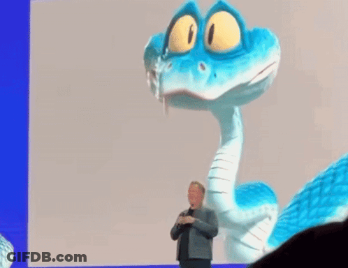A Man In A Suit Stands In Front Of A Blue And White Cartoon Snake GIF