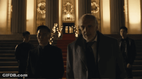 A Man In A Suit Stands In Front Of A Building GIF