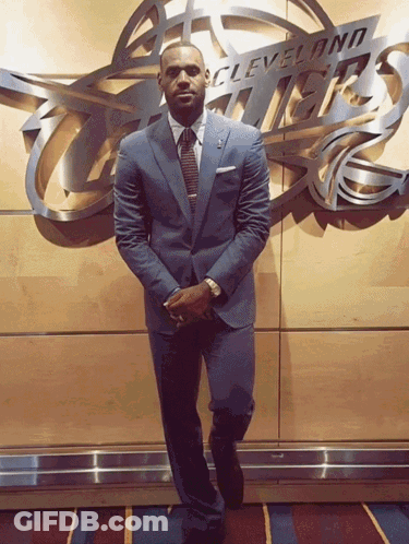 A Man In A Suit Stands In Front Of A Cleveland Thunder Sign GIF