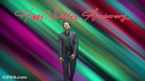 A Man In A Suit Stands In Front Of A Colorful Background That Says " Happy Wedding Anniversary " GIF