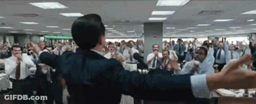 A Man In A Suit Stands In Front Of A Crowd Of People GIF