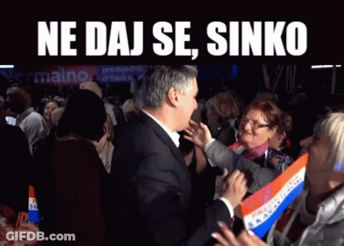 A Man In A Suit Stands In Front Of A Crowd With The Words Ne Daj Se Sinko On The Top GIF