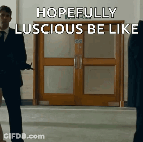 A Man In A Suit Stands In Front Of A Door That Says Hopefully Luscious Be Like On It GIF