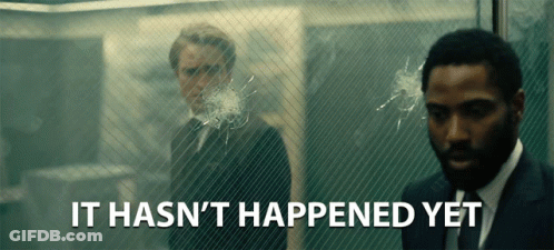 A Man In A Suit Stands In Front Of A Glass Wall With The Words " It Hasn 'T Happened Yet " Below Him GIF