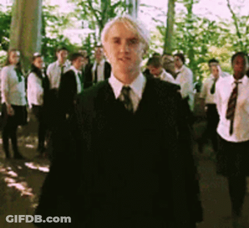 A Man In A Suit Stands In Front Of A Group Of People GIF