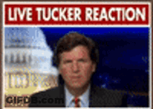 A Man In A Suit Stands In Front Of A Live Tucker Reaction Sign GIF