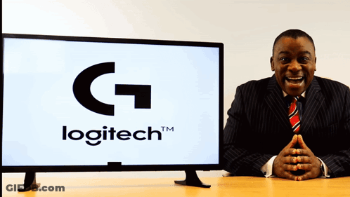 A Man In A Suit Stands In Front Of A Logitech Monitor GIF