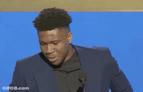 A Man In A Suit Stands In Front Of A Microphone GIF
