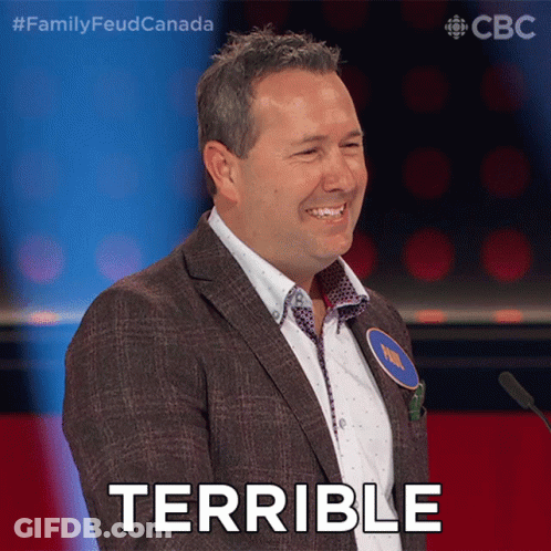 A Man In A Suit Stands In Front Of A Microphone With The Word Terrible On His Face GIF