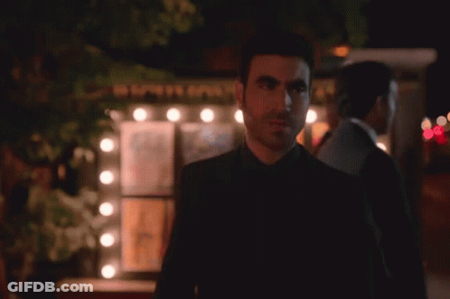 A Man In A Suit Stands In Front Of A Mirror GIF