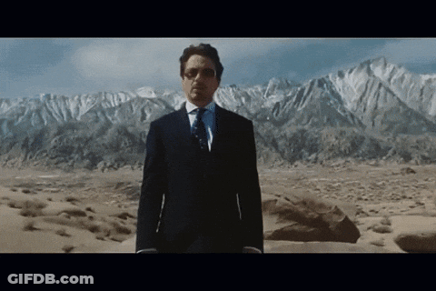 A Man In A Suit Stands In Front Of A Mountain Range GIF