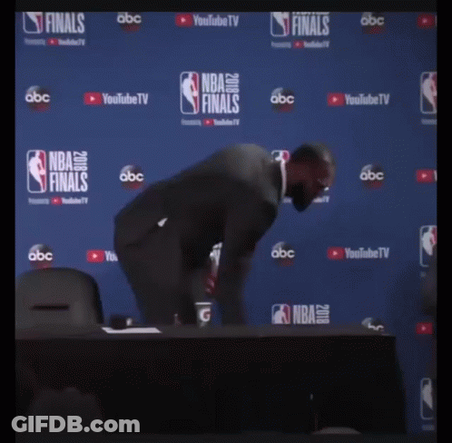A Man In A Suit Stands In Front Of A Nba Finals Wall GIF