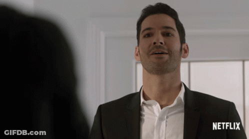 A Man In A Suit Stands In Front Of A Netflix Sign GIF