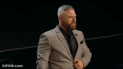 A Man In A Suit Stands In Front Of A Pink Shirt GIF