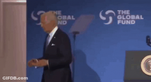 A Man In A Suit Stands In Front Of A Podium That Says The Global Fund On It GIF