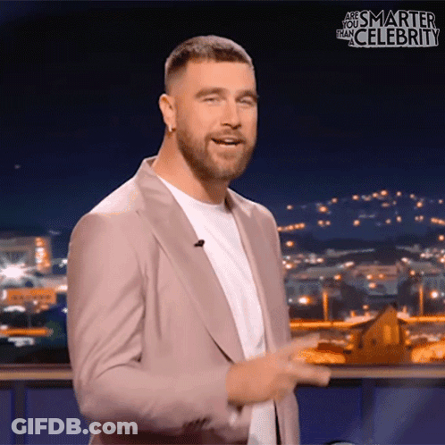 A Man In A Suit Stands In Front Of A Screen That Says " Are You Smarter Than Celebrity " GIF