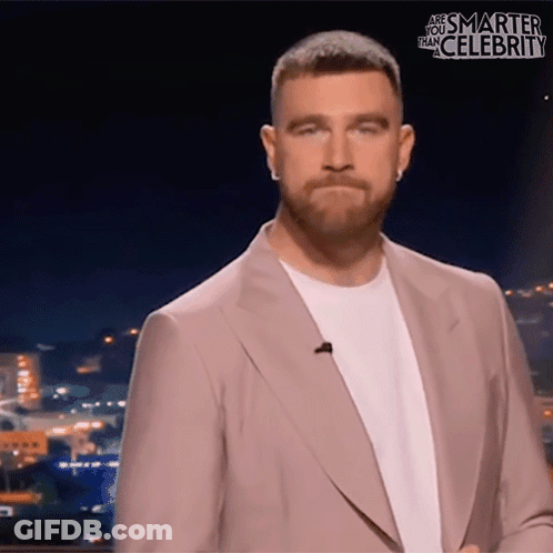 A Man In A Suit Stands In Front Of A Screen That Says " Are You Smarter Than Celebrity " GIF