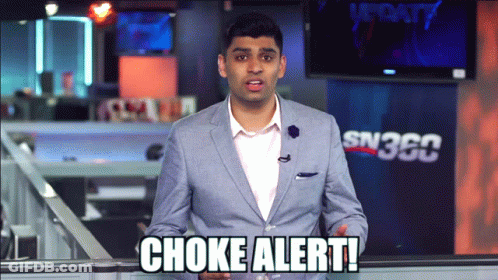 A Man In A Suit Stands In Front Of A Sign That Says Choke Alert GIF