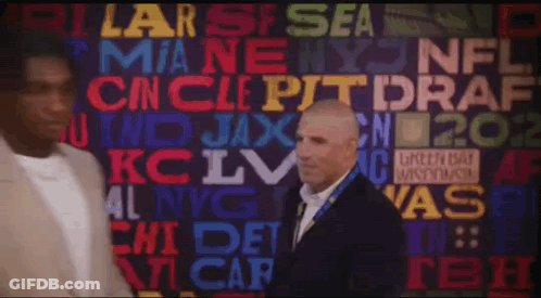 A Man In A Suit Stands In Front Of A Wall That Has The Word Draft On It GIF