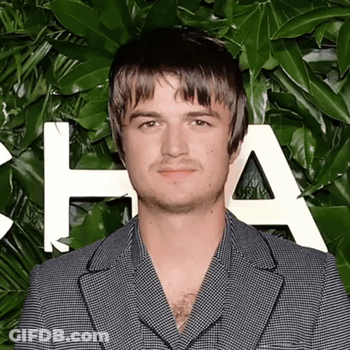 A Man In A Suit Stands In Front Of A Wall With The Letter A On It GIF