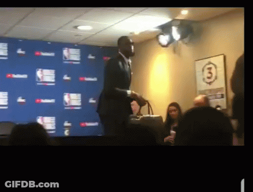 A Man In A Suit Stands In Front Of A Wall With The Number 3 GIF