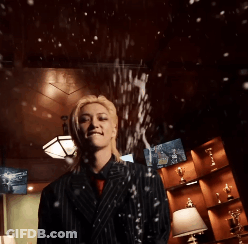 A Man In A Suit Stands In Front Of A Wall With Trophies GIF