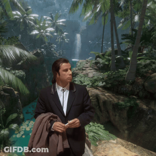 A Man In A Suit Stands In Front Of A Waterfall In The Jungle GIF
