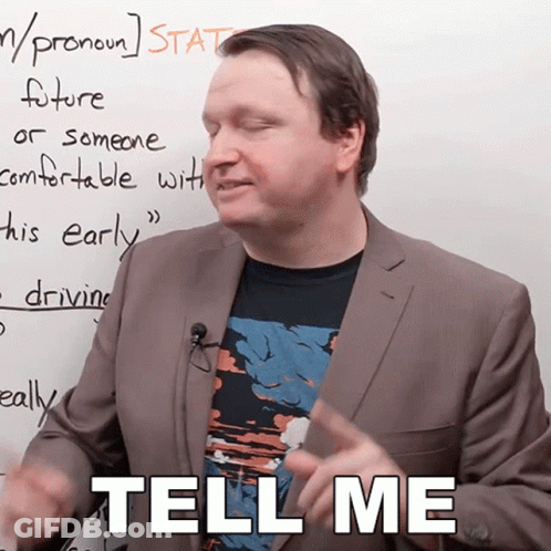 A Man In A Suit Stands In Front Of A White Board And Says Tell Me GIF