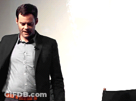 A Man In A Suit Stands In Front Of A White Wall GIF