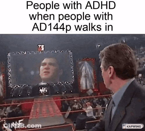 A Man In A Suit Stands In Front Of A Wrestling Ring With A Screen Behind Him That Says People With Adhd GIF
