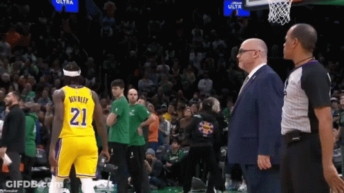 A Man In A Suit Stands Next To A Basketball Player Wearing The Number 21 GIF