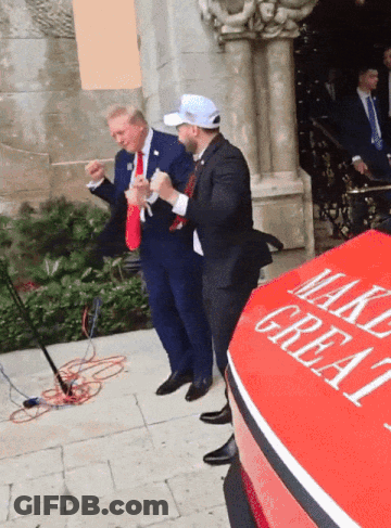 A Man In A Suit Stands Next To A Red Car That Says Make Great GIF