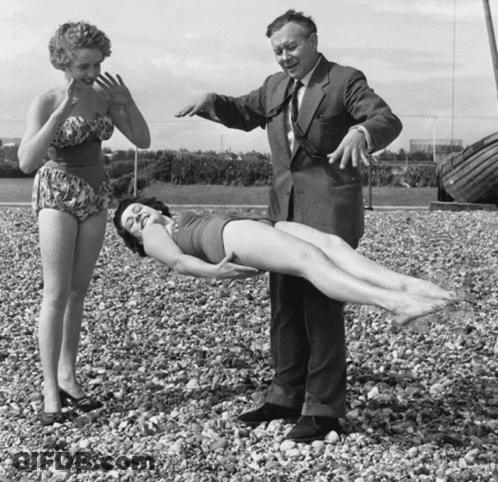 A Man In A Suit Stands Next To A Woman In A Bikini GIF
