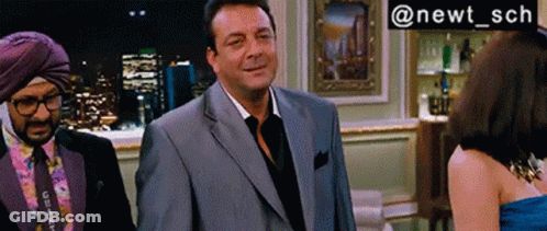A Man In A Suit Stands Next To A Woman In A Blue Dress And A Man In A Turban GIF