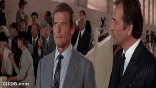 A Man In A Suit Stands Next To Another Man In A Suit And Tie GIF
