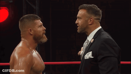 A Man In A Suit Stands Next To Another Man In A Suit GIF