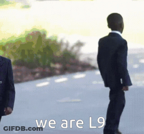 A Man In A Suit Stands Next To Another Man In A Suit With The Words We Are L9 Below Them GIF