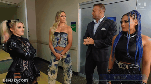 A Man In A Suit Stands Next To Two Women With The Name Giulia On The Bottom Right GIF