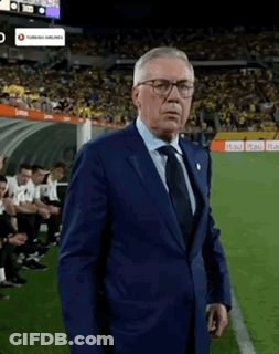 A Man In A Suit Stands On A Soccer Field GIF